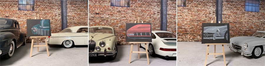 Varios cuadros expuestos junto a coches clásicos