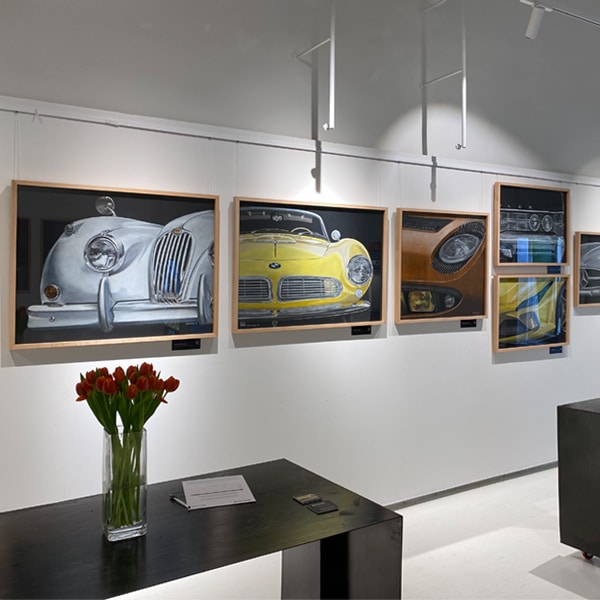 Detalle de los cuadros expuestos donde destacan un Jaguar XK 140 y un BMW 507